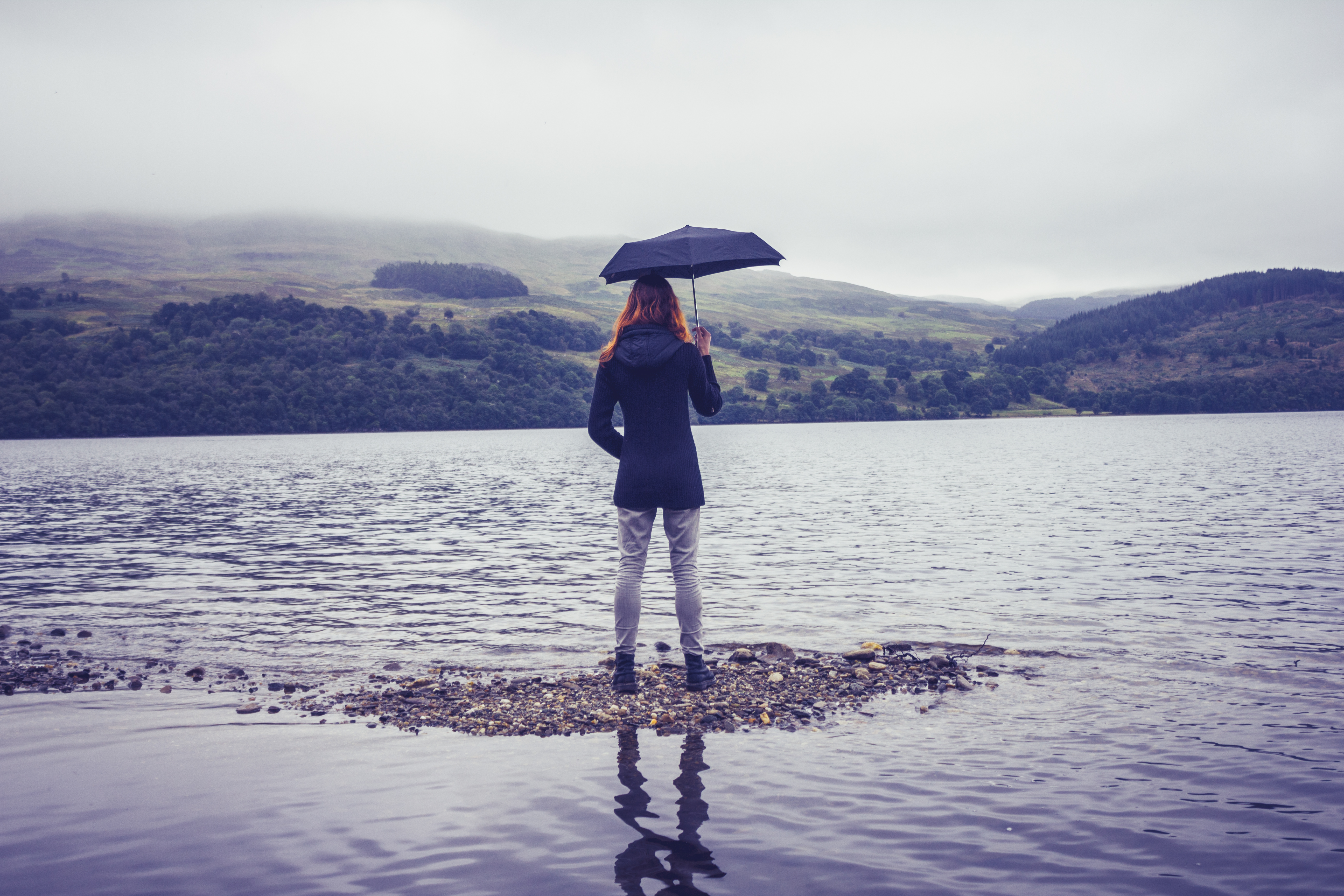 Young woman with an umbrella standing in lake